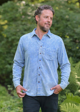 Load image into Gallery viewer, Man wearing a light blue button-up shirt standing outdoors with greenery in the background
