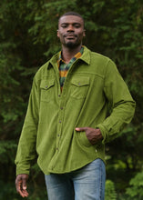 Load image into Gallery viewer, Man wearing a green jacket standing in front of trees
